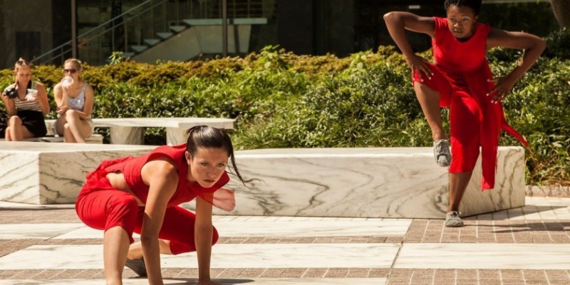 Image of a dancer in red outside in a dance position on the ground