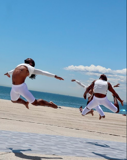 three men jumping at the beach in white costumes