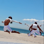 Dancers in white jumping in an arch position at the beach