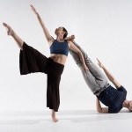 2 dancers pose, one standing raising one leg, the other inverted with his feet on her shoulder.