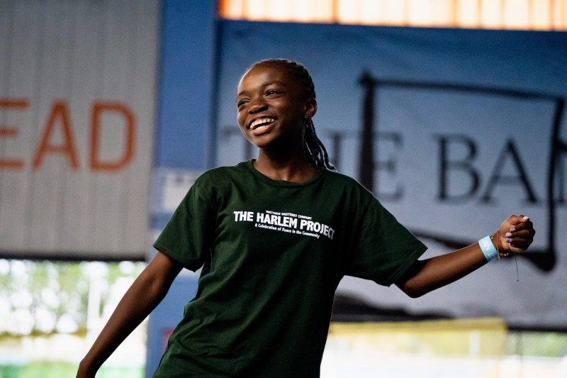 Young dancer performs and smiles, wearing a green t-shirt.