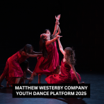 Five dancers wearing red dresses in a tableau, where all are reaching up.