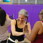 Two women laughing together and dancing at Dancewave's previous FREE Family Salsa Dance class.
