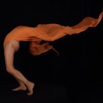 nude woman bent sharply backward draped in orange fabric