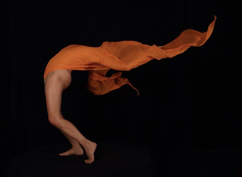 nude woman bent sharply backward draped in orange fabric