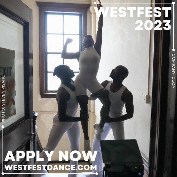 2 dancers support a 3rd dancer in the air as she reaches upward. They all wear white and are silhouetted in a door frame.