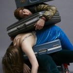 A photo of 3 people and suitcases piled on top of each other