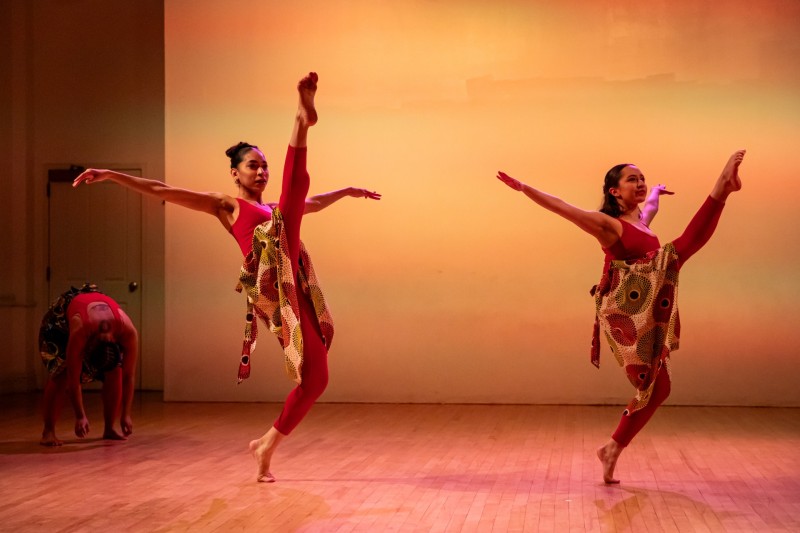 Two BIPOC cisgender woman are holding a hinge with their right leg and are on forced arch with their left foot.