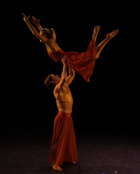 Dancer lifting another dancer above head lift.