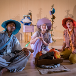 Three performers sitting on the floor in front of a felt fire