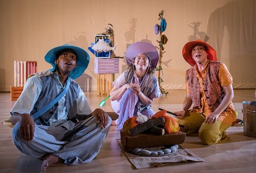 Three performers sitting on the floor in front of a felt fire