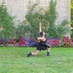 Dancer in a lunge dressed in black in front of a floral backdrop