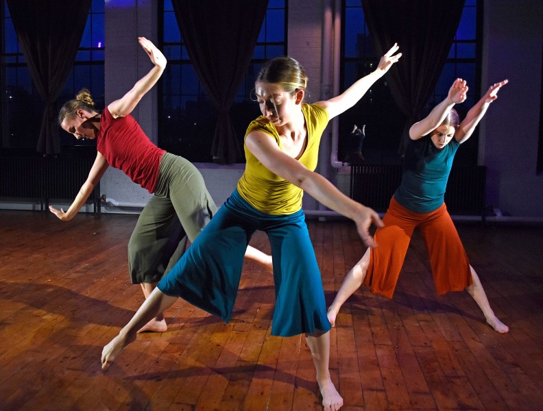 Dancers with their limbs at angles in brighly colored costumes. 