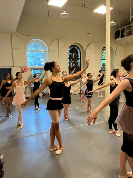 Adult ballet students practicing port de bras in the center