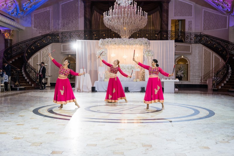3 dancers in colorful costumes in a white, spacious event space
