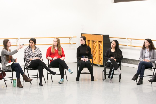 A group of teaching artists sitting in a circle listening to the instructor give direction. 