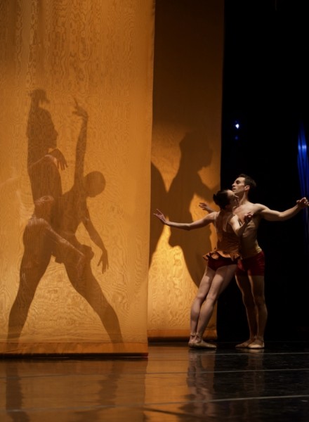 Dancers on stage in shadow with orange fabric
