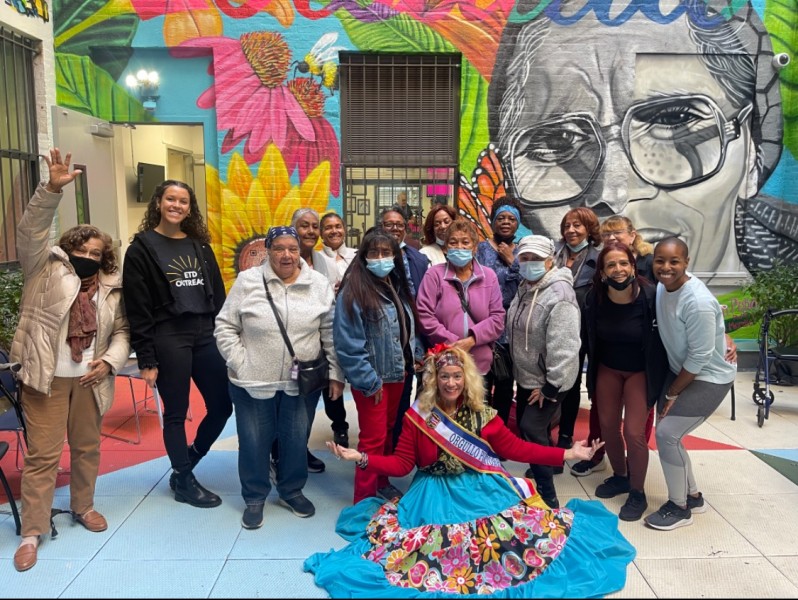 Participants gather in front of colorful mural at Loisaida Center