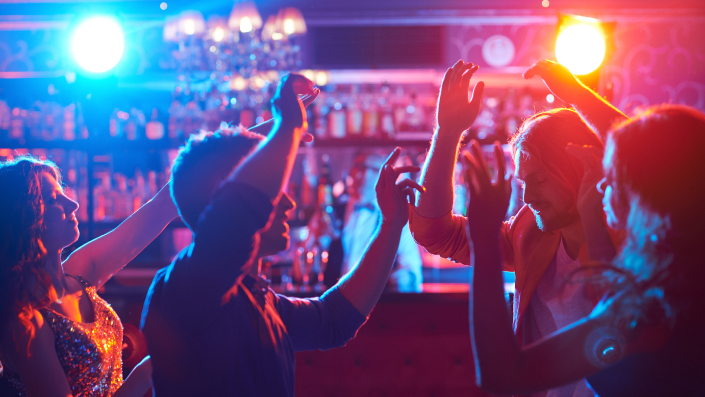 Photo of people dancing at a bar in blue and orange lighting