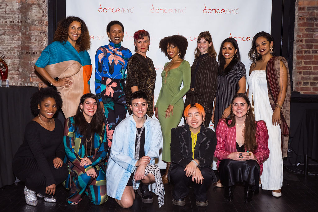 Dance/NYC staff photo. The staff poses, smiling, in front of the Dance/NYC step and repeat